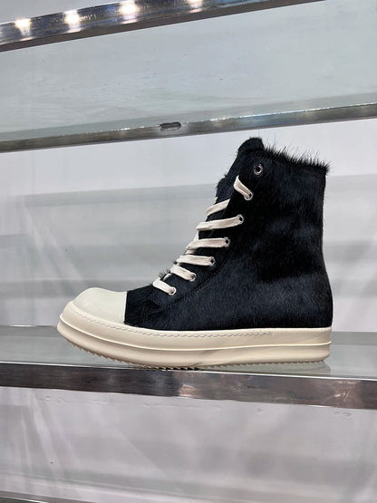 Schwarzer High-Top-Sneaker aus Leder mit weißer Sohle und Schnürsenkeln auf Metallregal.