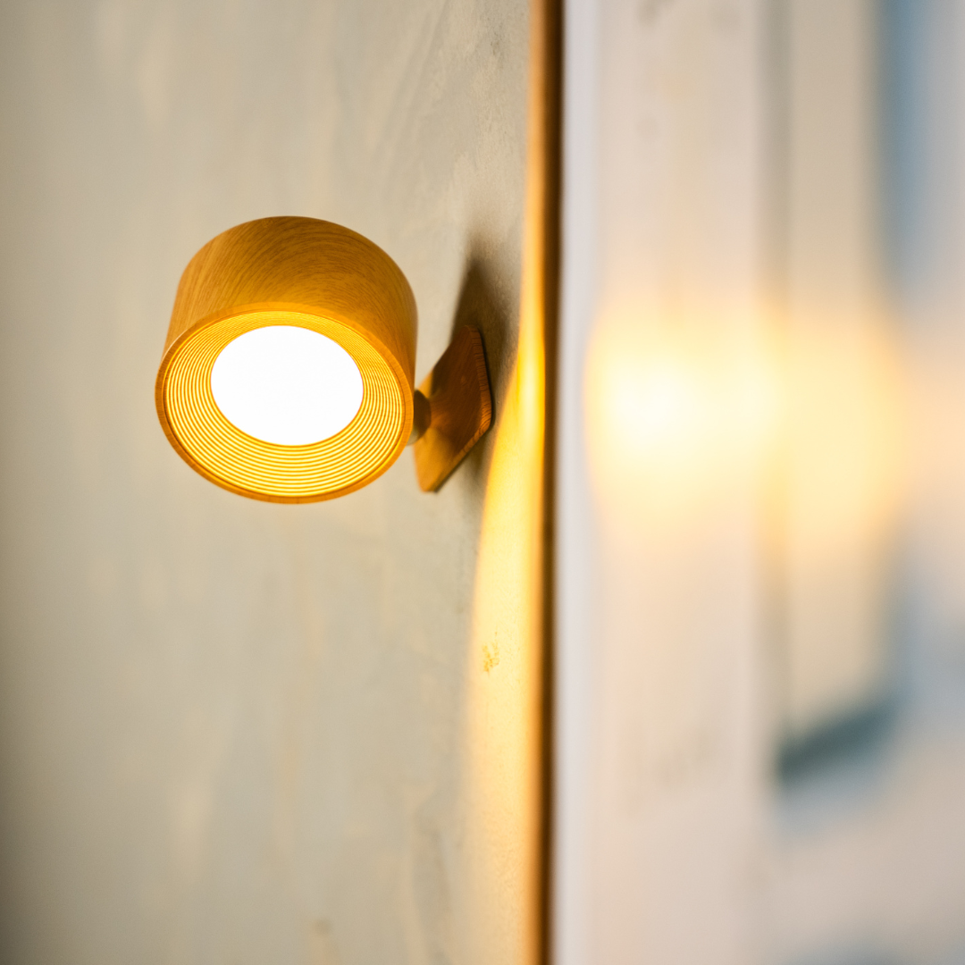 Närbild på en tänd vägglampa i träutförande, med tydliga ringar i den räfflade insidan och ett varmt, mjukt sken. 15
