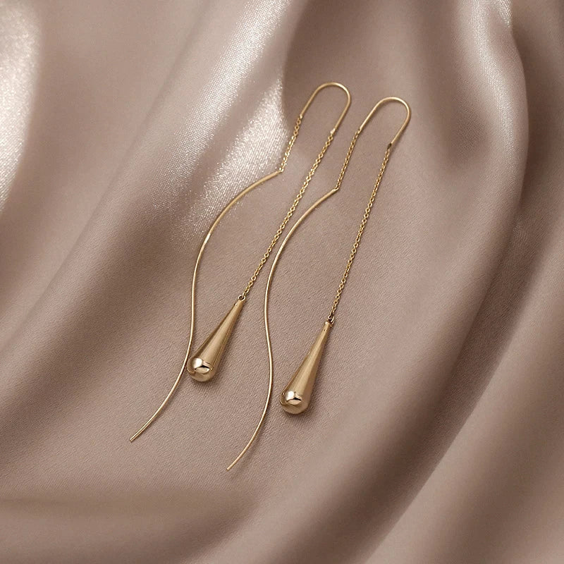 Goldene Ohrringe auf beigem Seidenstoff, minimalistisches Design, eleganter Schmuck.