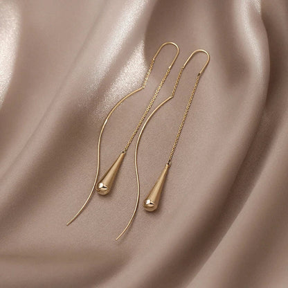 Goldene Ohrringe auf beigem Seidenstoff, minimalistisches Design, eleganter Schmuck.