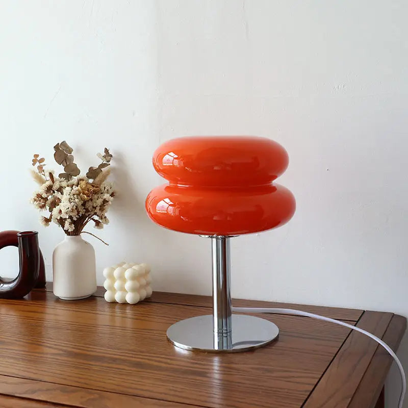 Orange Glaslampe auf Holztisch, moderne Tischleuchte, Inneneinrichtung, minimalistisches Design.
