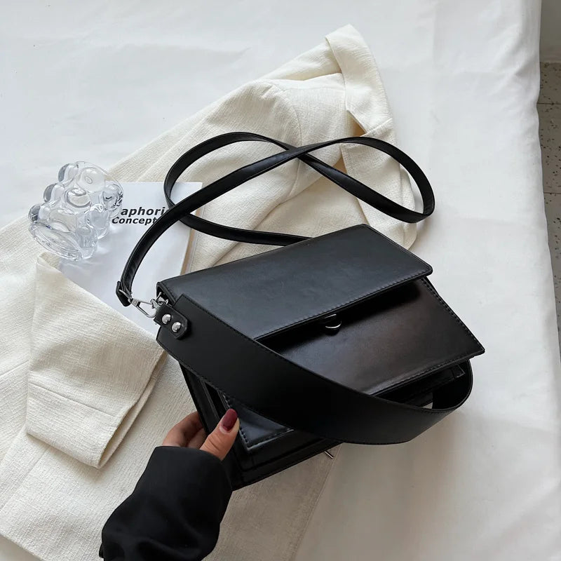 Schwarze Ledertasche mit breitem Riemen auf weißem Stoff, stilvolles Accessoire für Damen.