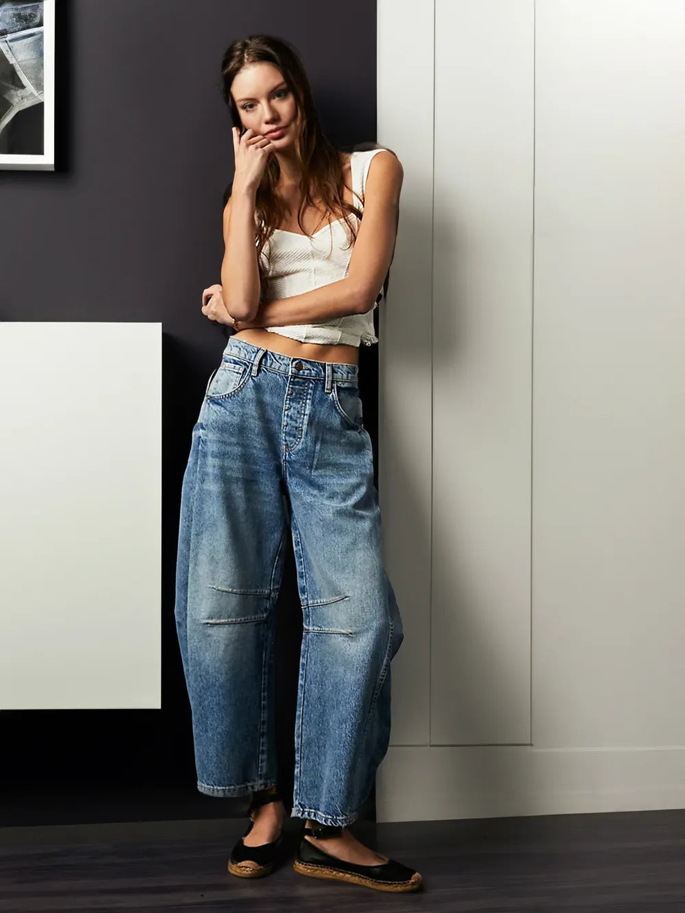 Frau in blauer Baggy-Jeans und weißem Top, lässiger Look, Modefotografie, moderne Kleidung.