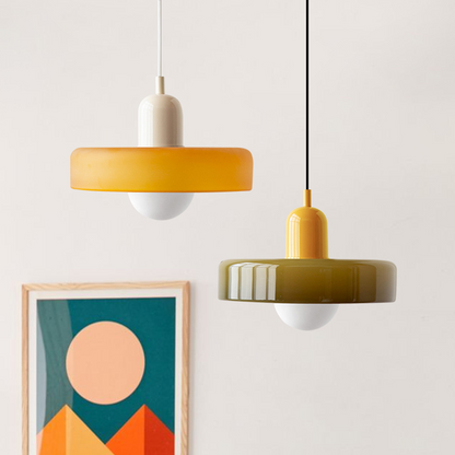 Zwei moderne Hängelampen, gelb und olivgrün, aus Glas, vor minimalistischem Hintergrund.