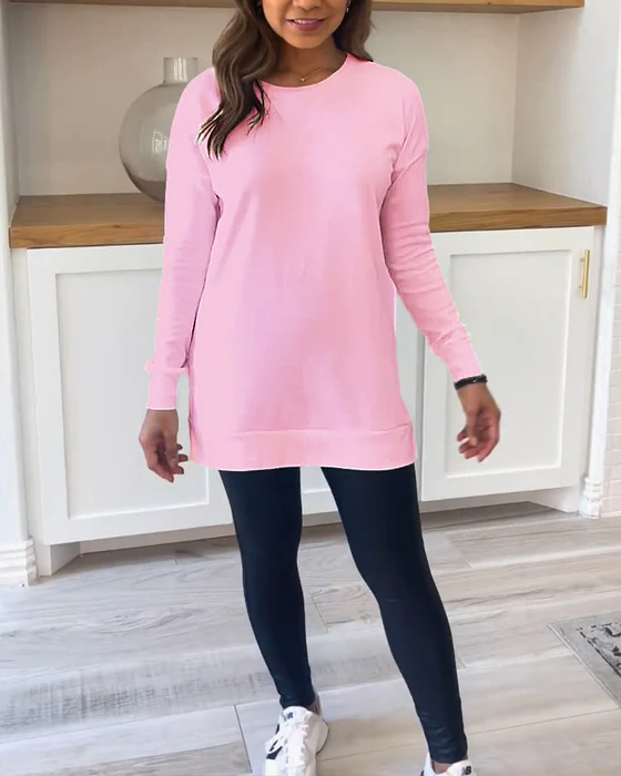 Frau in rosa Langarmshirt und schwarzen Leggings, lässige Mode, Wohnzimmer-Hintergrund.