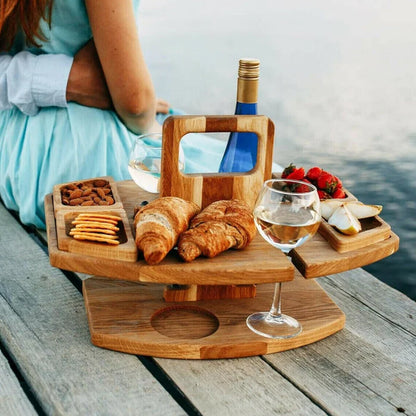 Picknicktisch aus Holz mit Weinhalter, Croissants, Erdbeeren, Käse, Nüssen und Crackern am See.