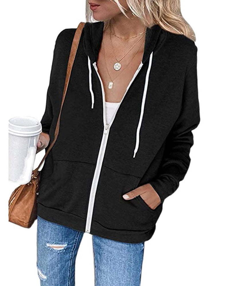 Frau in schwarzem Kapuzenpullover mit Reißverschluss, Kaffeebecher, Jeans, braune Tasche.