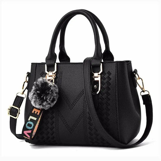 Schwarze Damenhandtasche mit Pompon-Anhänger, verstellbarem Riemen, Lederoptik.