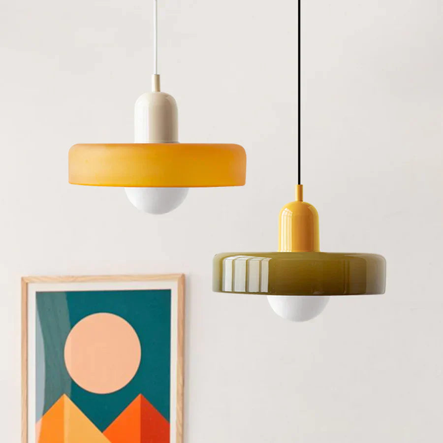 Zwei moderne Hängelampen, gelb und olivgrün, aus Glas, vor abstraktem Kunstwerk.