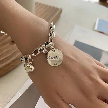 Silberarmband mit Herz- und Smile-Anhänger, S925, modisches Schmuckdesign.