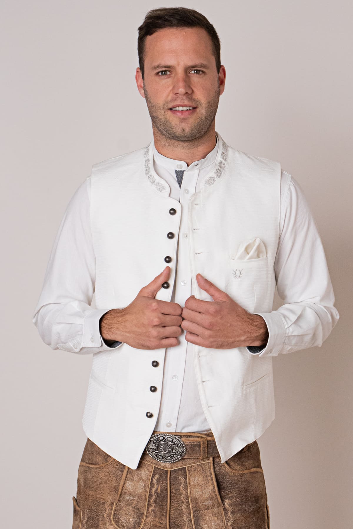 Mann in weißer Trachtenweste und Lederhose, traditionelles bayerisches Outfit, festliche Kleidung.