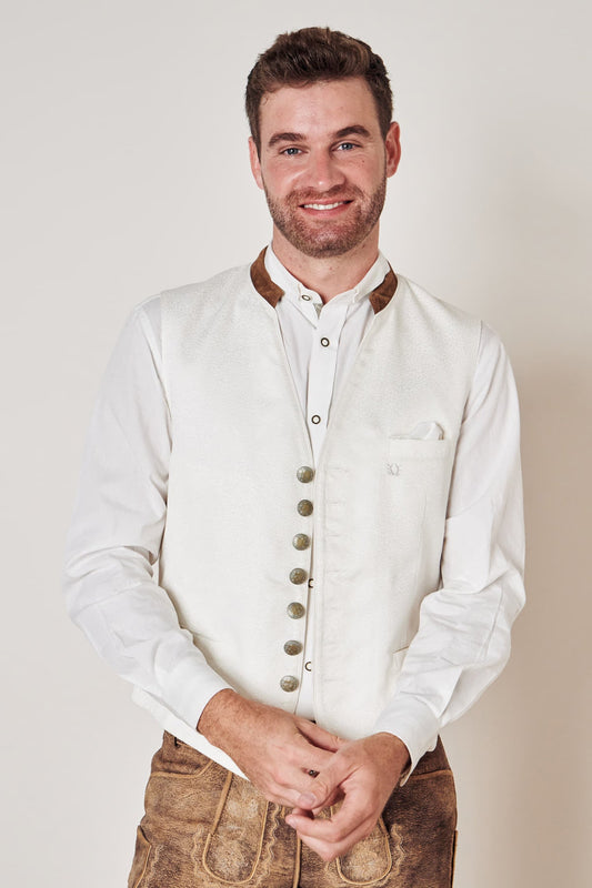 Mann in weißer Trachtenweste mit braunen Knöpfen und Lederhose, traditionelles bayerisches Outfit.