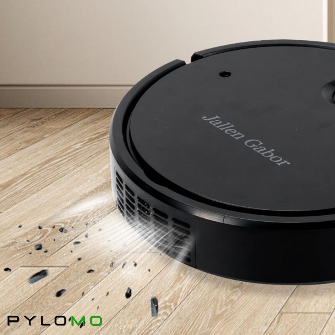 Närbild på svart robotdammsugare som suger upp smulor och damm från ett trägolv, med ventilationsöppningar på sidan. 5