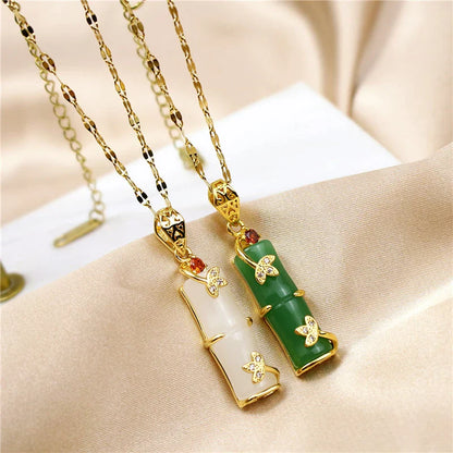 Zwei Anhänger aus Jade und Gold mit Schmetterlingsdesign auf goldener Kette, luxuriöser Schmuck.