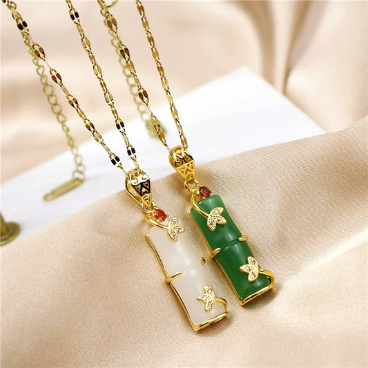 Zwei Anhänger aus Jade und Gold mit Schmetterlingsdesign auf goldener Kette, luxuriöser Schmuck.