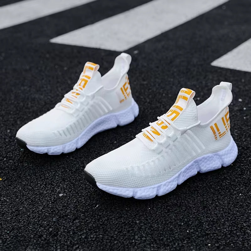 Weiße Sportschuhe mit gelben Akzenten auf Asphalt, atmungsaktives Mesh, rutschfeste Sohle.