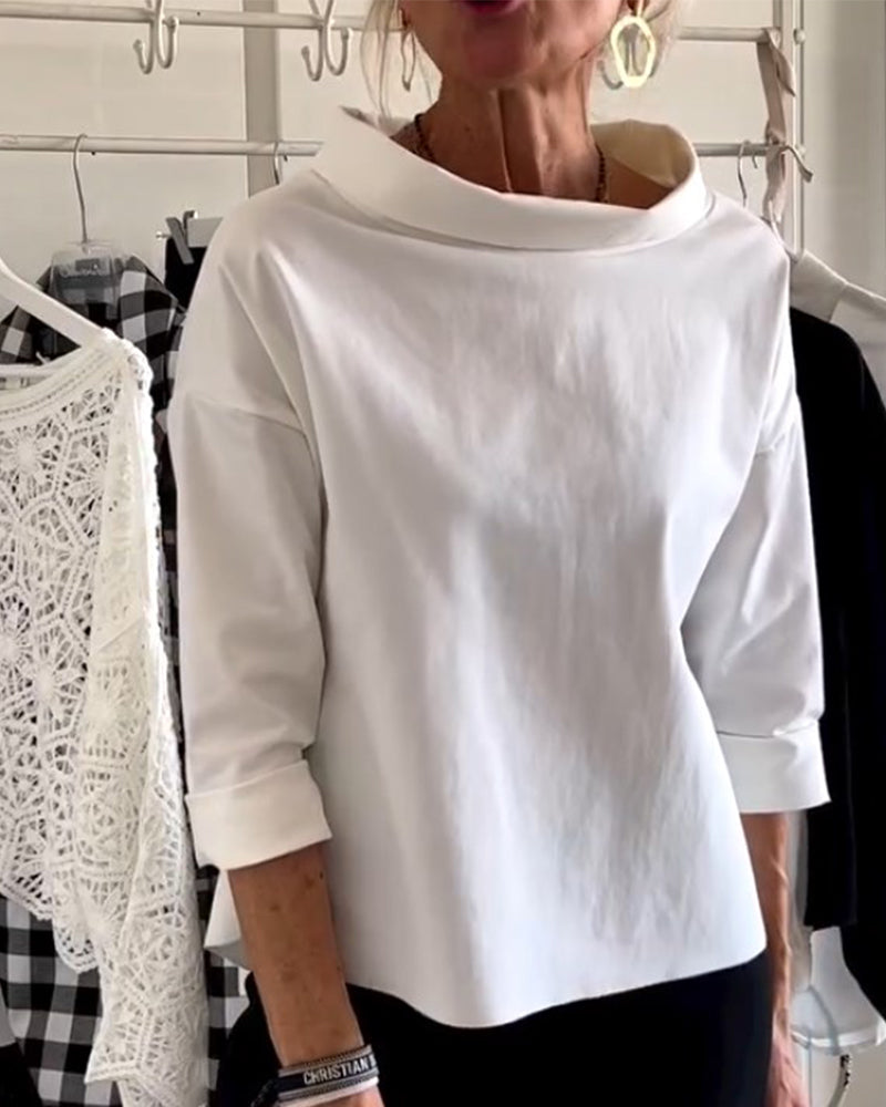 Frau in weißem, langärmligem Oberteil aus Baumwolle, modisch, elegant, vor Kleiderständer.