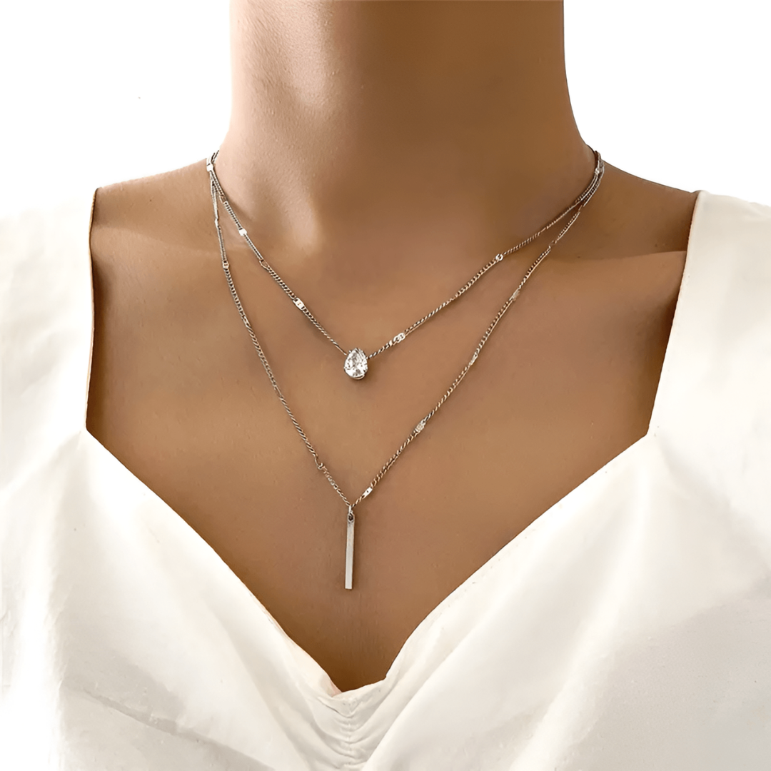 Frau trägt silberne Halskette mit Tropfenanhänger, eleganter Schmuck, modisches Accessoire.