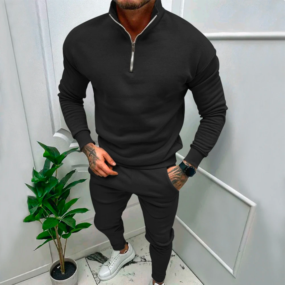 Mann in schwarzem Trainingsanzug mit Reißverschluss, weiße Sneaker, moderne Herrenmode.