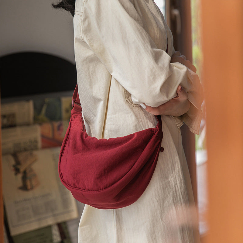 Frau mit roter Umhängetasche aus Stoff, lässiger Stil, modisches Accessoire, Tageslicht.