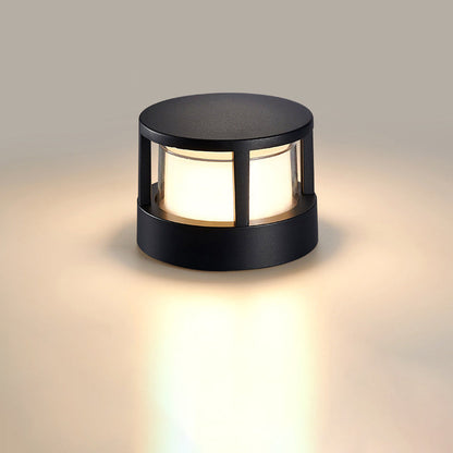 Rund svart lampa med tak och lysande vit skärm, fotograferad mot en neutral beige bakgrund. 8