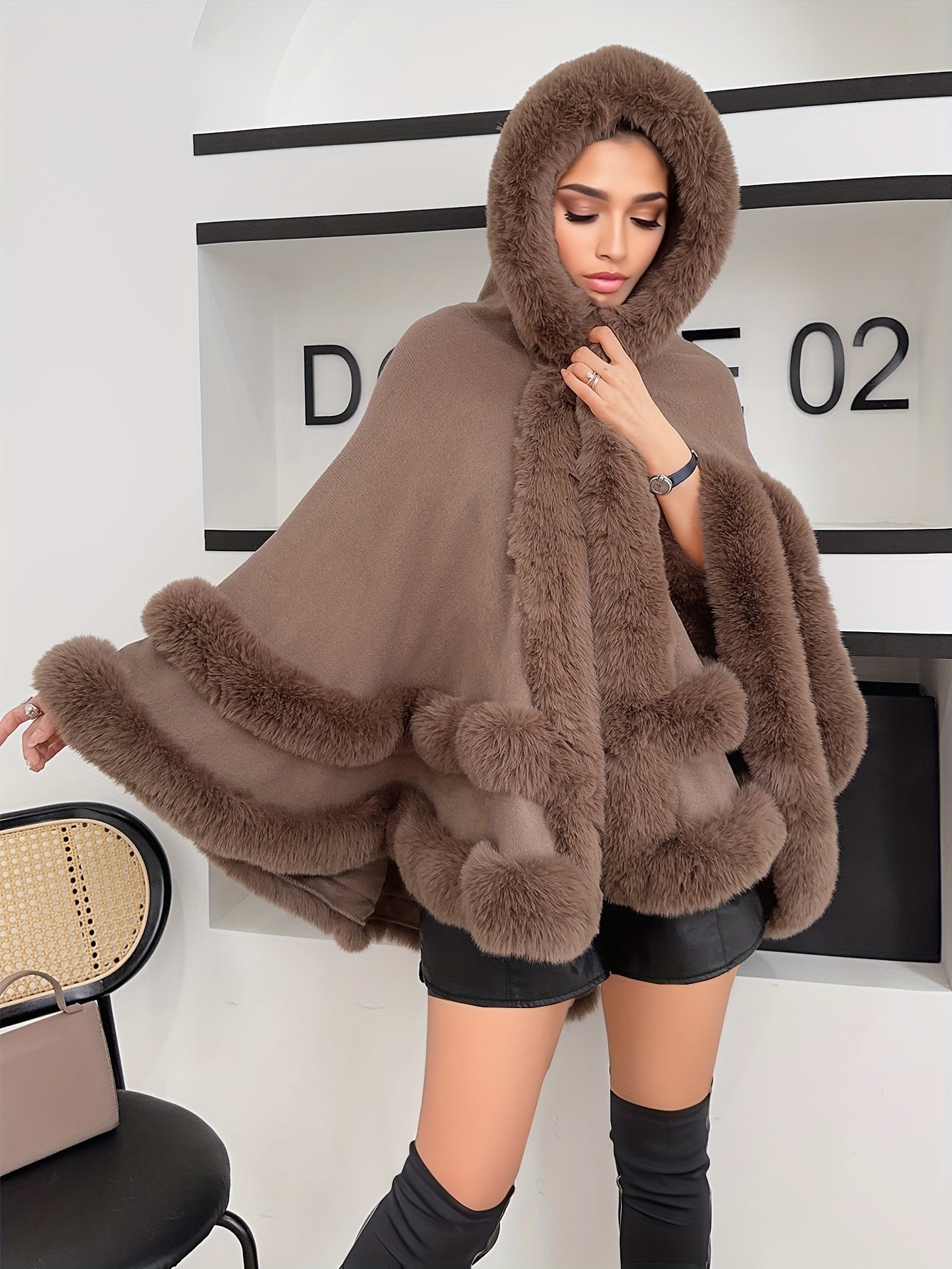 Frau in braunem Kapuzenponcho mit Kunstfellbesatz, modisch, elegant, Herbst-Winter-Outfit.