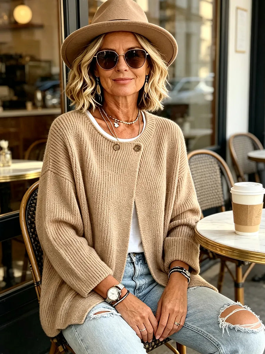Kvinna med hatt och solglasögon sitter på ett café i den beigea ribbstickade koftan 5