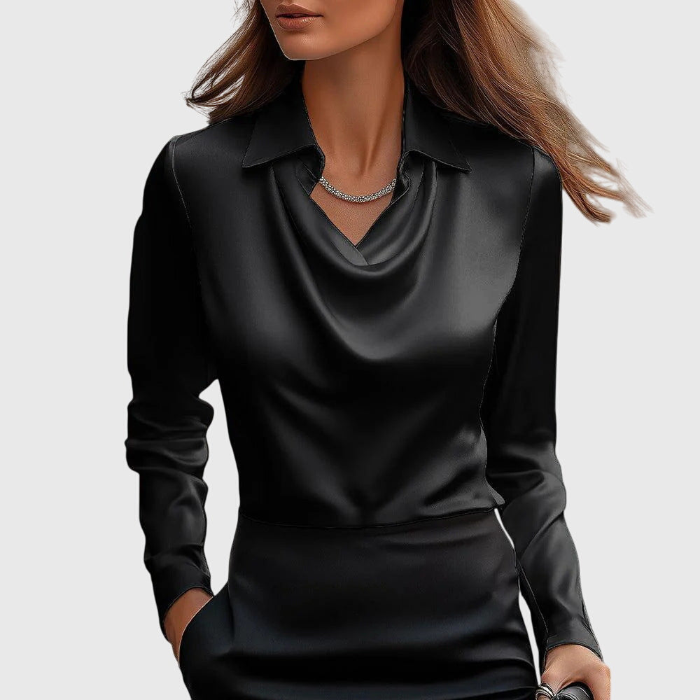 Modell bär den enfärgade svarta satinblusen med draperad hals och krage, med svart kjol och ett glittrande halsband. 3