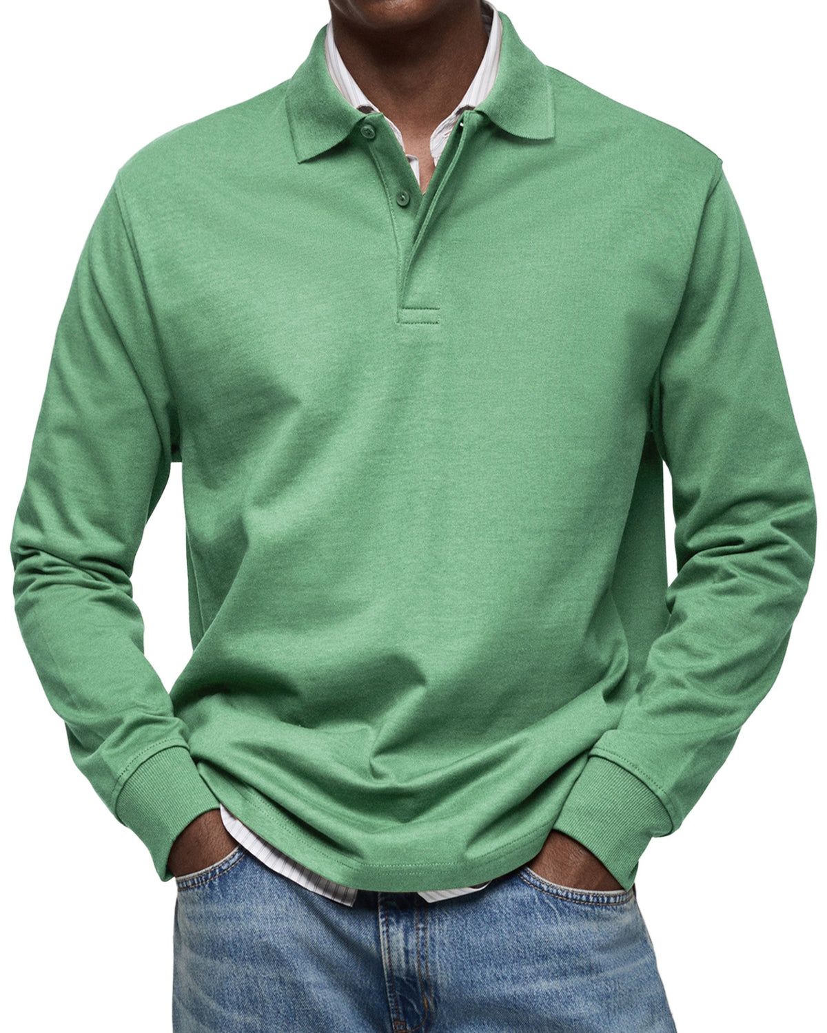 Grön långärmad pikétröja sedd framifrån på en modell, med polokrage och knappgylf, över randig skjorta och jeans. 7