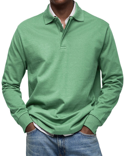 Grön långärmad pikétröja sedd framifrån på en modell, med polokrage och knappgylf, över randig skjorta och jeans. 7