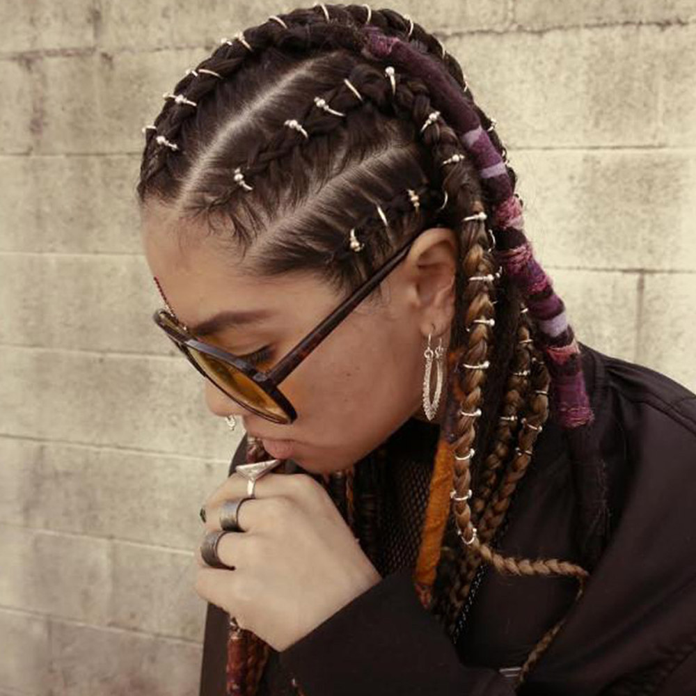 Frau mit geflochtenem Haar, goldene und silberne Haarspangen, Vintage-Schmuck, Sonnenbrille.