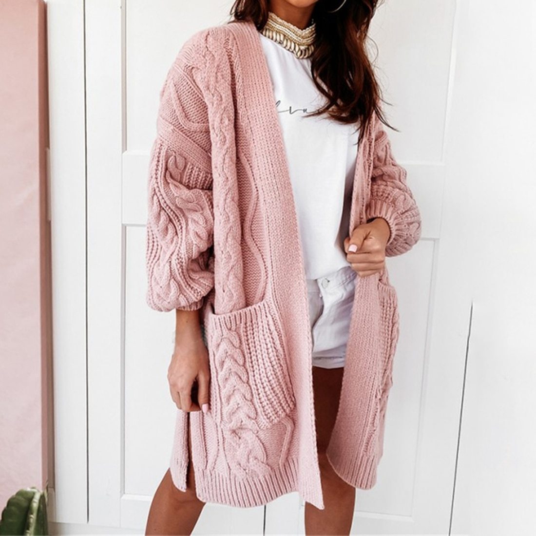 Frau trägt rosa Strickjacke mit Zopfmuster, lässig, modisch, gemütlich, Damenmode.