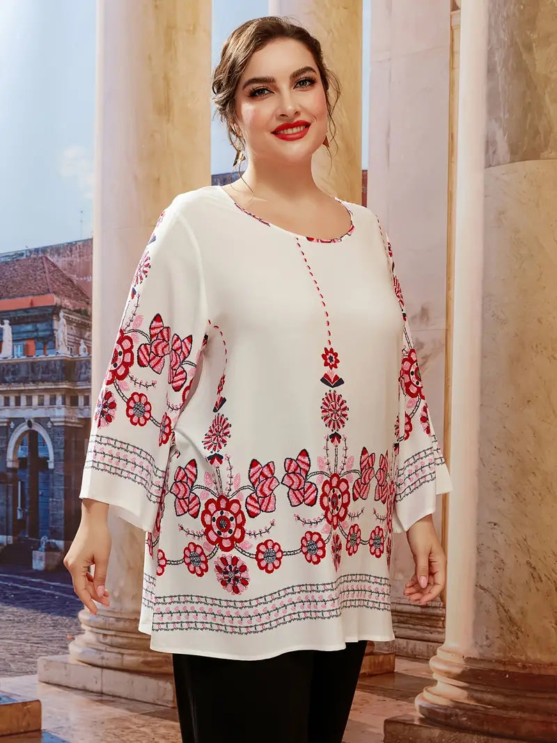 Frau in weißer Bluse mit roten Blumenmustern, lächelnd, vor Säulen stehend.