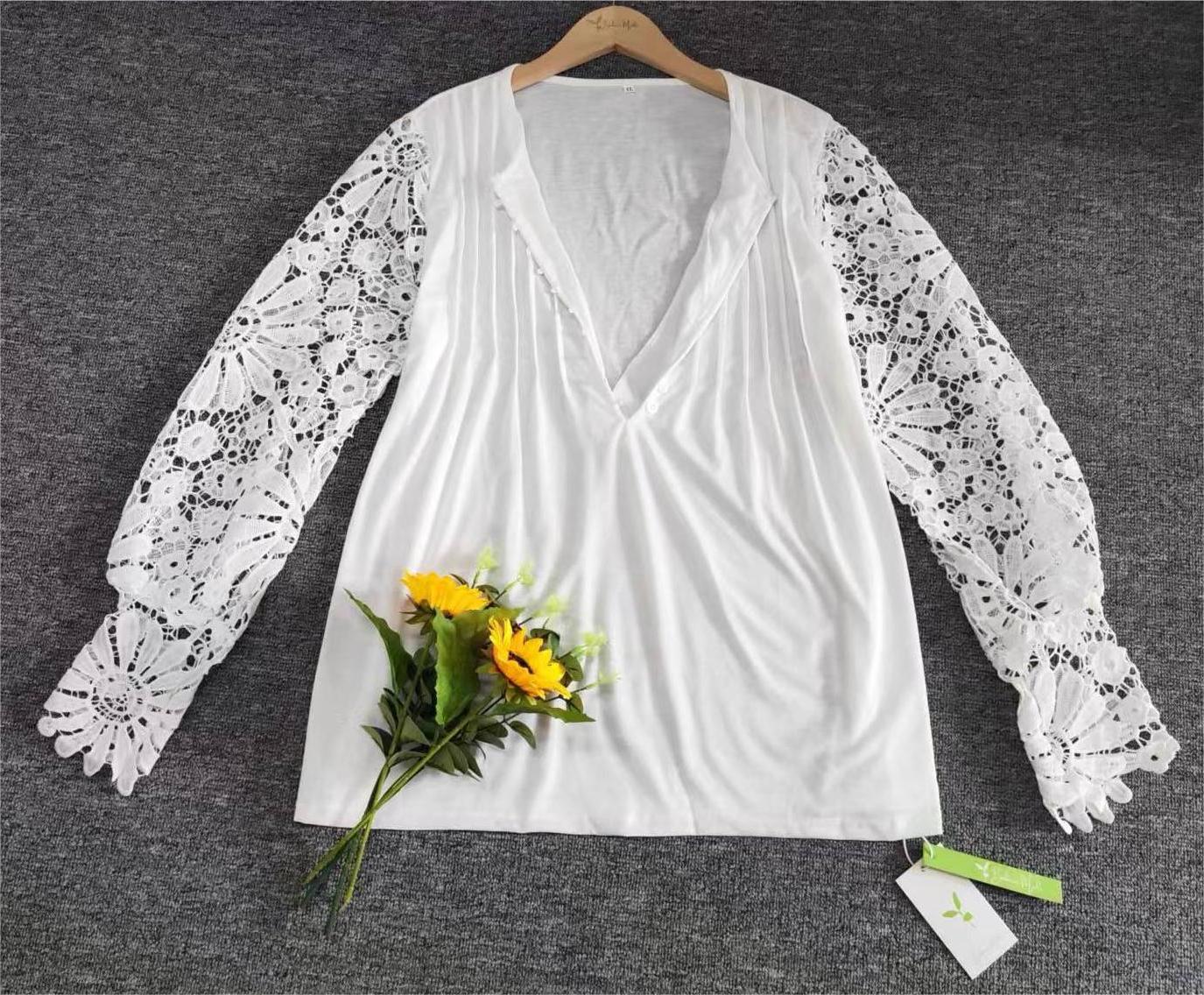Weiße Bluse mit Spitzenärmeln und V-Ausschnitt, auf grauem Hintergrund, mit Sonnenblumenstrauß.