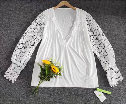 Weiße Bluse mit Spitzenärmeln und V-Ausschnitt, auf grauem Hintergrund, mit Sonnenblumenstrauß.