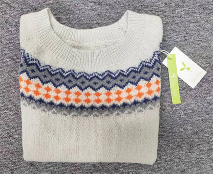 Beigefarbener Strickpullover mit blau-orangefarbenem Zickzackmuster auf grauem Hintergrund.
