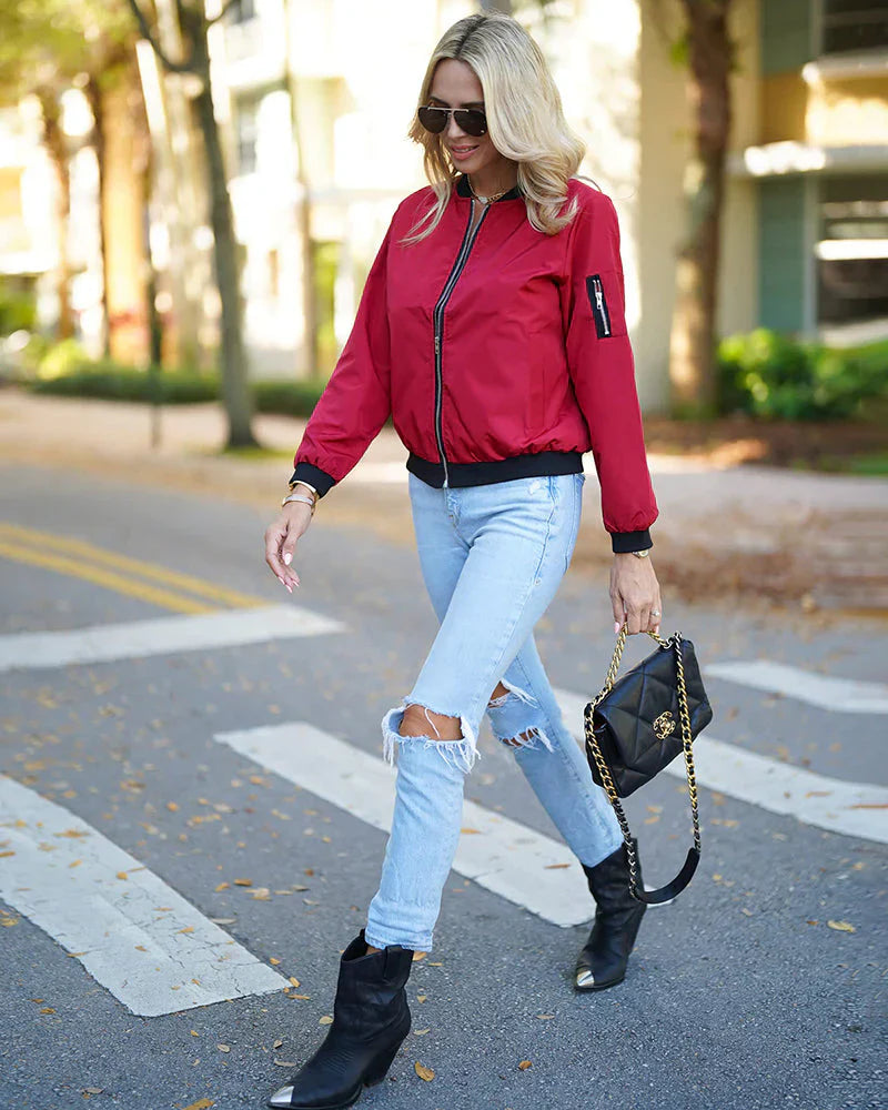 Frau in roter Bomberjacke, zerrissene Jeans, schwarze Stiefel, Handtasche, Straße, Herbstmode.