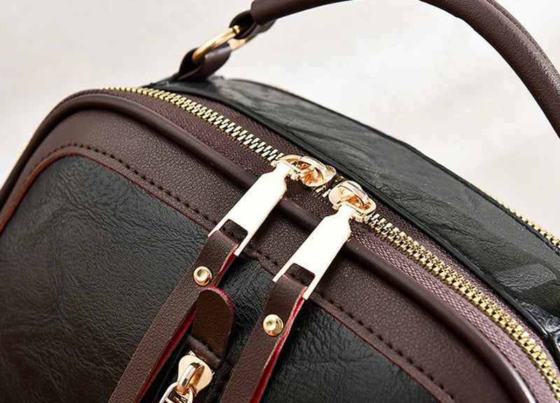 Braune Lederhandtasche mit goldenen Reißverschlüssen und Griff, elegante Damenmode.