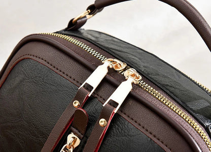 Braune Lederhandtasche mit goldenen Reißverschlüssen und Griff, elegante Damenmode.
