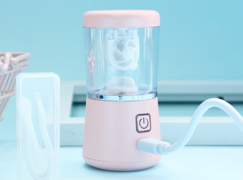 Rosa tragbarer Mini-Mixer mit USB-Anschluss, ideal für Smoothies und Shakes, auf blauem Hintergrund.