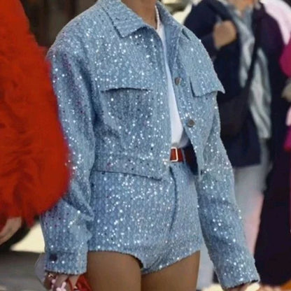 Person in glitzerndem, blauem Pailletten-Set, Jacke und Shorts, modisch, urbaner Stil.