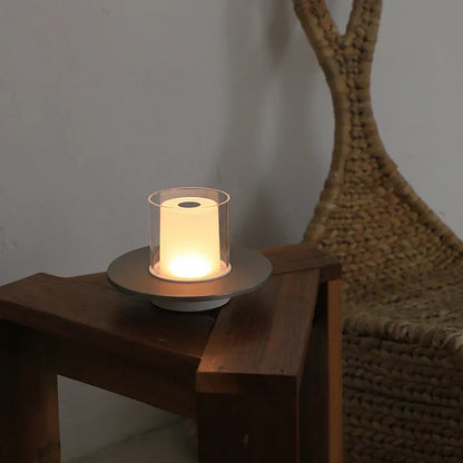 Moderne Tischlampe aus Glas und Metall auf Holztisch, warmes Licht, skandinavisches Design.