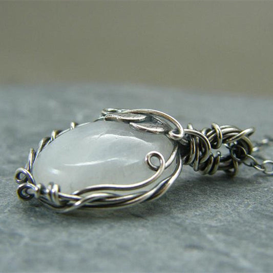 Silberner Drahtanhänger mit weißem Edelstein, handgefertigter Schmuck, elegantes Design.