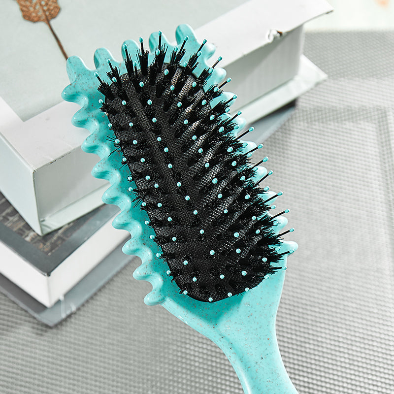Türkise Haarbürste mit schwarzen Borsten auf grauem Hintergrund, ideal für Haarpflege.