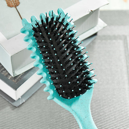 Türkise Haarbürste mit schwarzen Borsten auf grauem Hintergrund, ideal für Haarpflege.