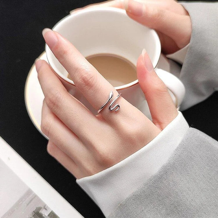 Silberner Ring an Hand mit Kaffeetasse, elegantes Schmuckdesign, minimalistisch, Damenmode.
