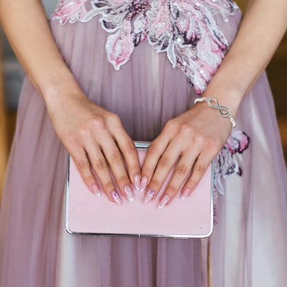 Frau in rosa Abendkleid hält rosa Clutch, elegante Maniküre, Schmuckarmband.