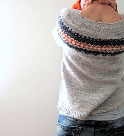 Person in grauem Strickpullover mit buntem Muster, Rückansicht, lässige Freizeitkleidung.