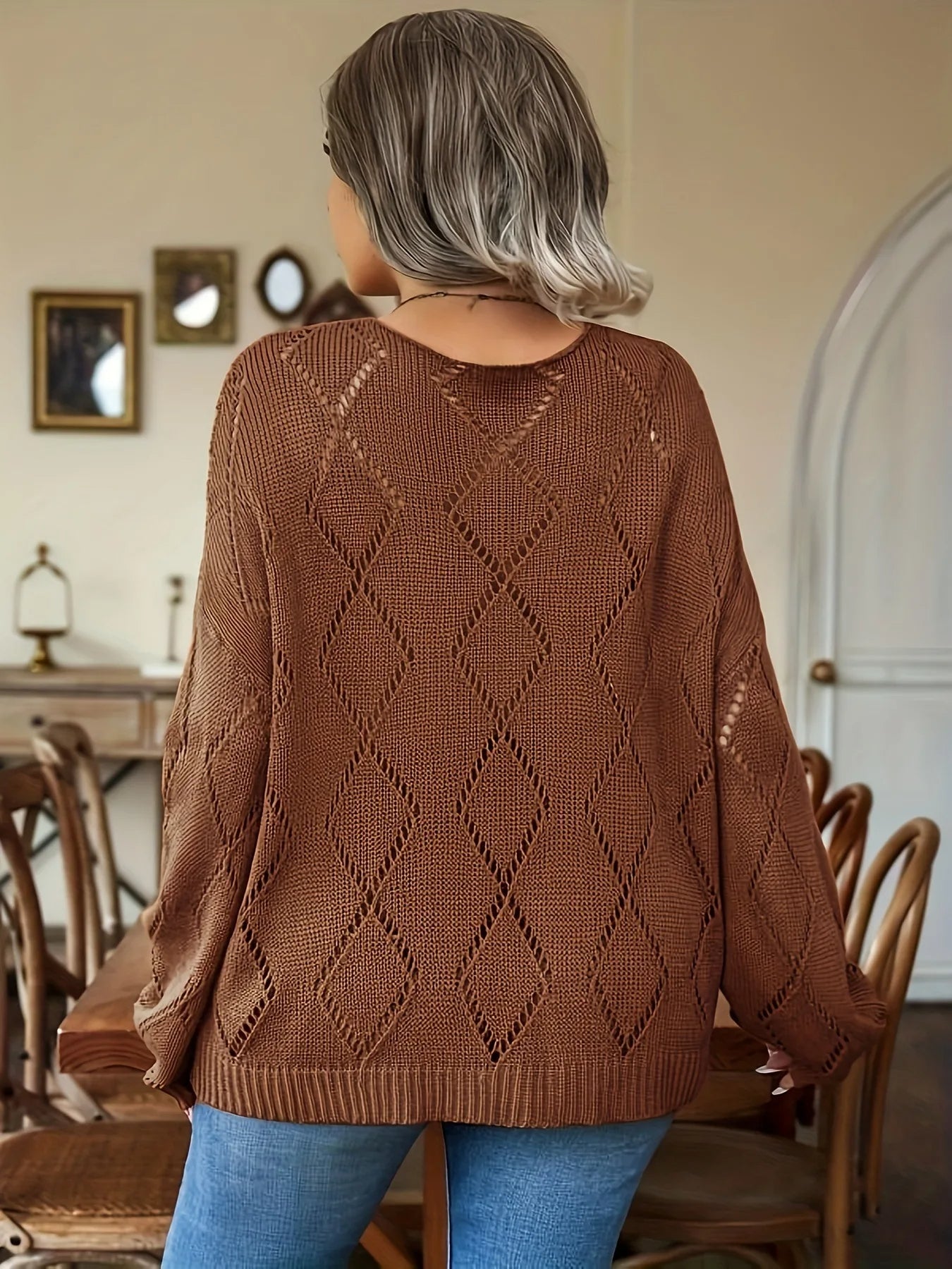 Frau in braunem Strickpullover mit Rautenmuster, sitzt in gemütlichem Esszimmer.