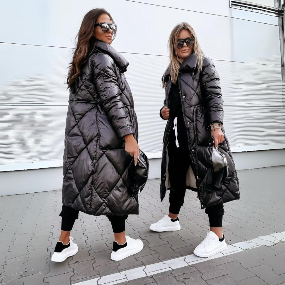 Två kvinnor i svarta quiltade kappor och vita sneakers, den ena sedd bakifrån och den andra framifrån, utomhus på gatsten. 4